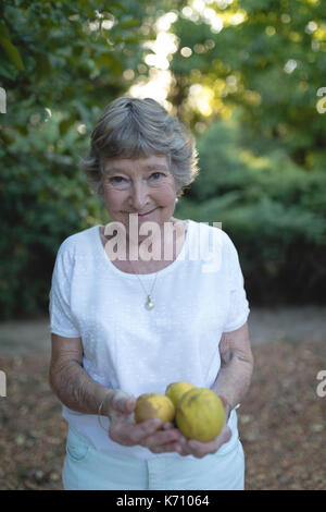 Portrait of senior woman holding fruits au jardin Banque D'Images