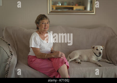 Portrait of senior woman sitting with dog on sofa in living room Banque D'Images