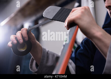 Les mains coupées de joueur de hockey sur glace masculin taping stick dans vestiaire Banque D'Images