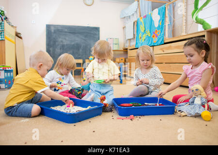 Groupe d'enfants jouant avec du riz et des haricots dans le jardin d'enfants Banque D'Images