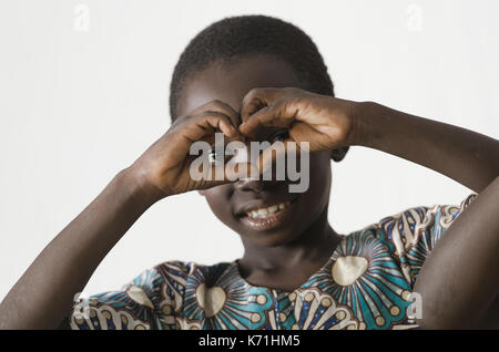 Petit enfant noir de l'Afrique montrant le symbole de coeur avec ses mains, isolated on white Banque D'Images