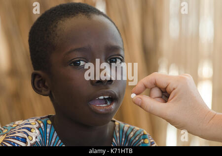 Docteur blanc donne un comprimé à un petit noir African boy Banque D'Images