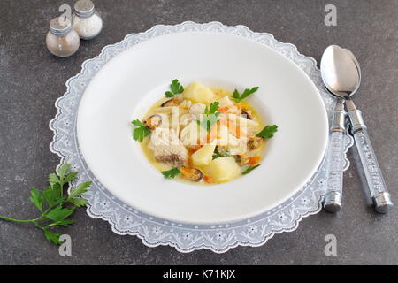 Soupe crémeuse avec un filet de poisson et les moules dans une assiette blanche sur une toile blanche sur un fond gris. saine alimentation. concept de vie méditerranéenne Banque D'Images