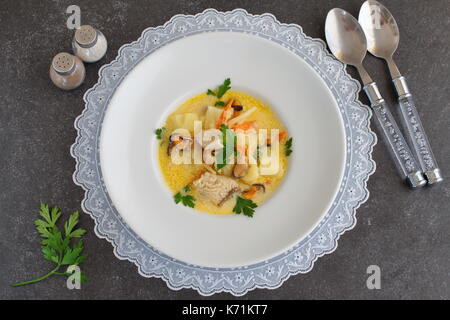 Soupe crémeuse avec un filet de poisson et les moules dans une assiette blanche sur une toile blanche sur un fond gris. saine alimentation. concept de vie méditerranéenne Banque D'Images