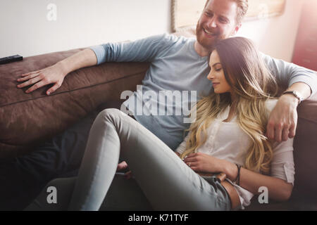 Heureux couple lying on sofa together et de détente à la maison Banque D'Images