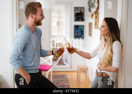 Couple heureux de boire une bière et toasting at home Banque D'Images