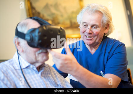 Crefelkd, Allemagne. 14Th sep 2017. la démence et l'alzheimer. friedhelm caspers, chef gériatrie médecin, mettre une paire de lunettes de réalité virtuelle sur un patient atteint de démence dans creveld, Allemagne, le 14 septembre 2017. assistance numérique devrait ralentir les processus de démence et d'Alzheimers. Les patients peuvent se déplacer à travers des scènes de rue à partir des années 1950, et ainsi faire un voyage dans leur propre passé. photo : marius becker/dpa/Alamy live news Banque D'Images