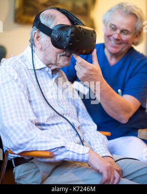 Crefelkd, Allemagne. 14Th sep 2017. la démence et l'alzheimer. friedhelm caspers, chef gériatrie médecin, mettre une paire de lunettes de réalité virtuelle sur un patient atteint de démence dans creveld, Allemagne, le 14 septembre 2017. assistance numérique devrait ralentir les processus de démence et d'Alzheimers. Les patients peuvent se déplacer à travers des scènes de rue à partir des années 1950, et ainsi faire un voyage dans leur propre passé. photo : marius becker/dpa/Alamy live news Banque D'Images