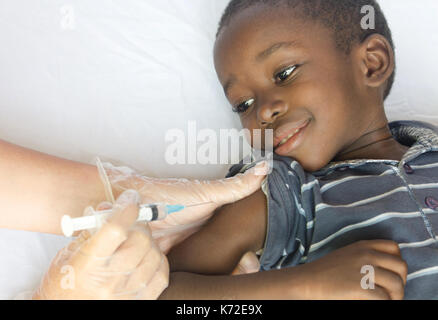 Heureux enfant africain reçoit une injection avec une aiguille d'un médecin volontaire blanc Banque D'Images