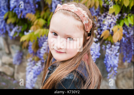 Printemps portrait of cute kid fille aux fleurs de glycines sur arrière-plan Banque D'Images