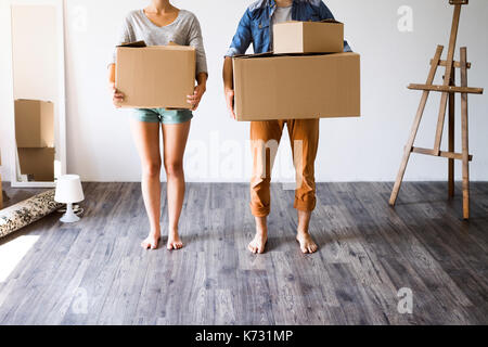 Méconnaissable deux jeunes mariés déménagement dans maison neuve, holding big boîtes de carton. Banque D'Images