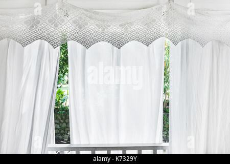 Des rideaux blancs avec des motifs sur la véranda de bois résidentiel. balcon de style rustique, de la lumière du soleil à partir de la fenêtre . Banque D'Images