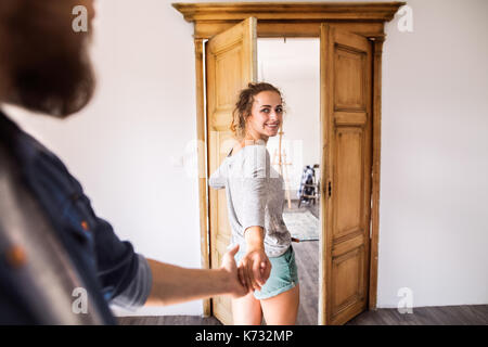 Deux jeunes mariés déménagement dans maison neuve, femme homme par la main, entrant par la porte. Banque D'Images