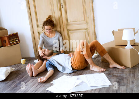 Deux jeunes mariés déménagement en nouvelle chambre, allongé sur le sol près des boîtes de carton, de repos. Banque D'Images