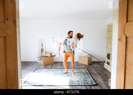 Deux jeunes mariés déménagement dans une nouvelle maison, exercent sur l'homme femme dans ses bras. Banque D'Images