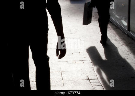 Silhouette floue et l'ombre d'une femme portant un sac et un homme après sa, rue de la ville dans la nuit Banque D'Images