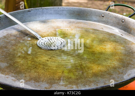 Grande télévision poêle ou poêlon pour la paella ou jambalaya sur brûleur gaz. processus de chauffage de l'huile d'olive pour la cuisson des viandes et des légumes avec du riz d'été. Banque D'Images