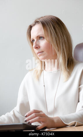 Beaux Cheveux blonds, jeune femme de 30 à 40 ans, travailler sur ordinateur dans bureau. vertical close up portrait candide. Banque D'Images