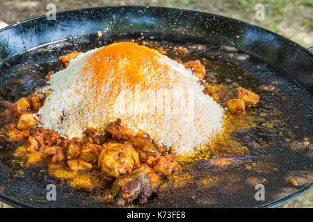 Tas de riz non cuit à sec dans une grande télévision pan prêt à être mélangé avec de la viande de poulet frit d'épices et de sauce tomate. processus de la cuisson de la paella ou jambalaya. Banque D'Images