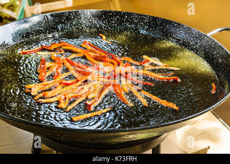 Processus de friture poivron capsicum de bandes dans l'huile d'olive grésillante dans télévision pan. préparer les ingrédients pour la paella, ou à l'extérieur, weeken jambalaya. Banque D'Images