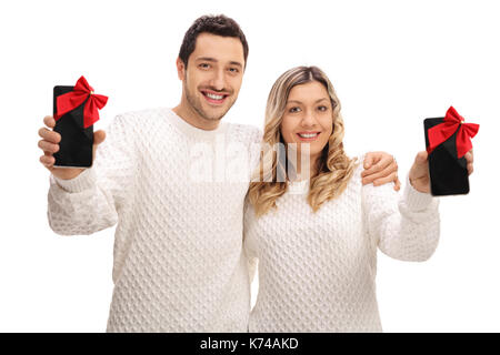 Jeune couple montrant un téléphone enveloppé de rubans rouges en tant que cadeaux isolé sur fond blanc Banque D'Images