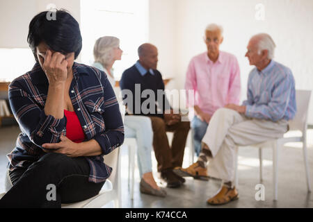 Inquiets senior woman with friends in background in art class Banque D'Images