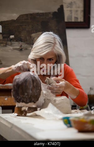 Attentifs senior woman faire une sculpture en argile en classe de dessin Banque D'Images