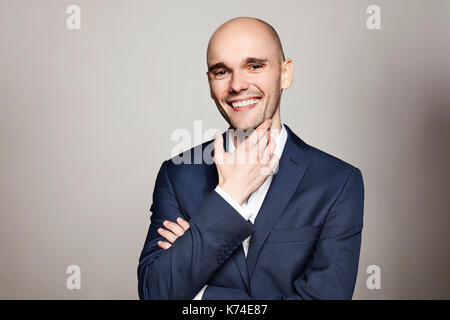 Portrait of young cheerful man in blue Jacket. il gratte le menton. Banque D'Images