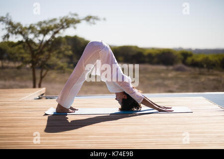 Woman practicing yoga on à la piscine sur une journée ensoleillée Banque D'Images