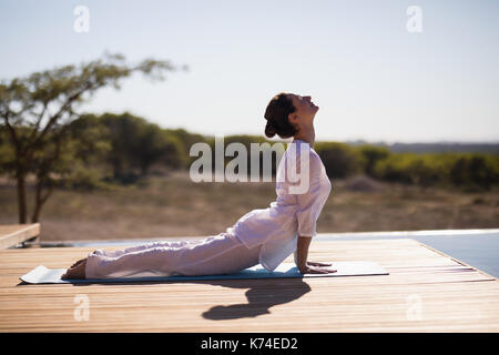 Woman practicing yoga on à la piscine sur une journée ensoleillée Banque D'Images