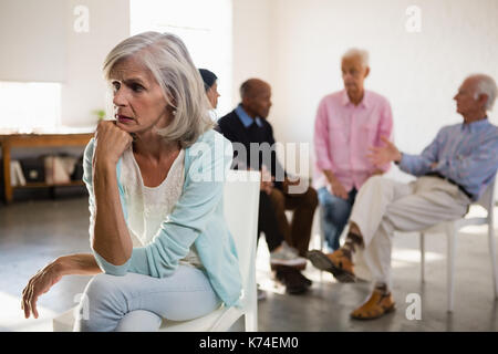 Senior femme inquiète avec des amis en arrière-plan dans la classe d'art Banque D'Images