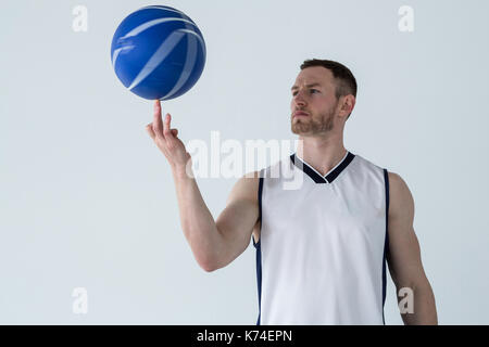 Joueur de basket-ball en rotation sur le doigt contre fond blanc Banque D'Images