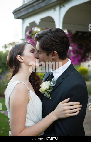 Romantic newlywed couple s'embrasser tout en se tenant dans park Banque D'Images