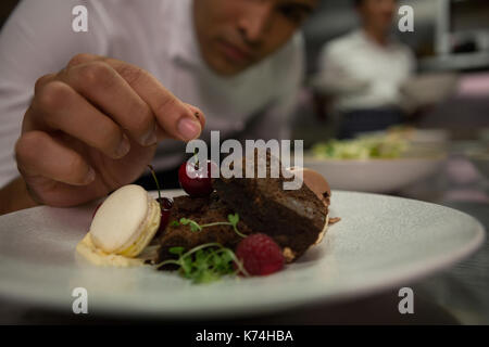 Close-up of male chef garniture dessert dans la plaque Banque D'Images