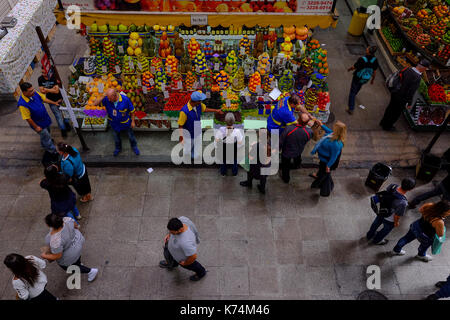 La vie dans le Mercado Municipal à Sao Paulo, Brésil avec des vendeurs et des costomers autour d'un stand de fruits et légumes, les gens marchant Banque D'Images