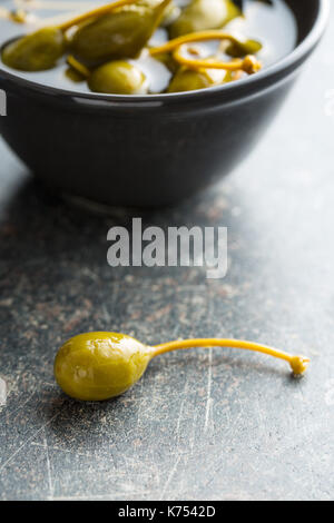 Petits fruits marinés caper sur la vieille table de cuisine. Banque D'Images