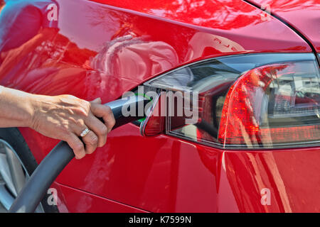 'S' Tesla Sedan connecté à 480 volts (charge rapide) Supercharger, hand inserting connexion d'alimentation. Banque D'Images