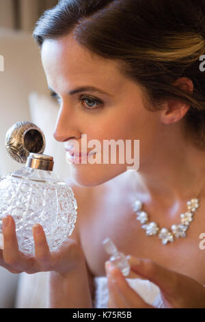 Close up of woman smelling perfume, assis sur un fauteuil à la maison Banque D'Images