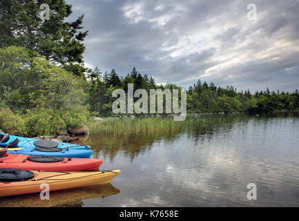 Un groupe de quatre, des kayaks attendre sur la rive du lac ou tôt le matin Banque D'Images