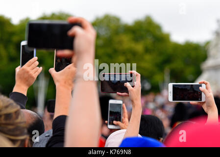 Quantité de caméras de téléphone mobile soulevées pour filmer et photographier la relève de la garde en passant l'Édifice commémoratif Victoria à Londres, au Royaume-Uni. Les téléphones intelligents Banque D'Images