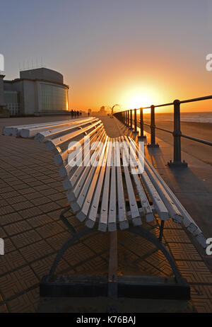 Coucher du soleil le long de la promenade du bord de mer avec un banc en premier plan à Ostende par sa plage de la mer du Nord avec une vue sur l'horizon à l'arrière-plan, la Belgique. Banque D'Images