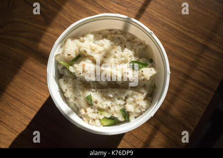 Close up of south Indian breakfast upma dans un grand bol en plastique sur un fond de bois Banque D'Images