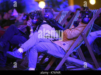 Editorial N'utilisez que la foule regarder sir Simon Rattle sur grand écran dans la cour de la sculpture du Barbican, joué sur les casques personnels, comme il dirige son premier concert en tant que directeur musical de l'orchestre symphonique de Londres au lieu de Londres. Banque D'Images