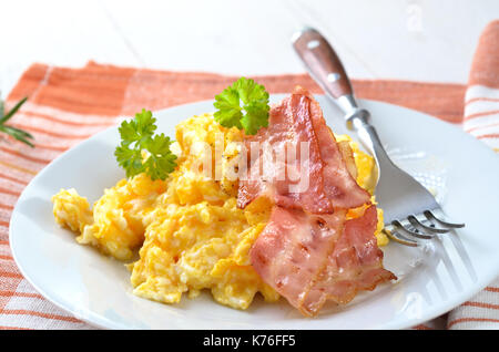 Oeufs brouillés avec lard grillé sur une plaque blanche Banque D'Images