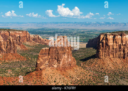 Monument national du Colorado après le lever du soleil avec le Monument de l'indépendance et la ville de Grand Junction en arrière-plan, Colorado, États-Unis. Banque D'Images