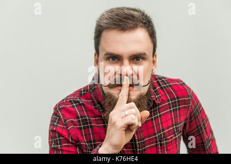 Chut signe. colère businessman avec barbe et moustache à la caméra au guidon avec silent signe. studio shot, sur fond gris. Banque D'Images