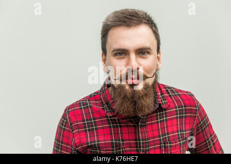 Les baisers de l'air et flirter. close up. portrait d'homme barbu rigolo. grey background, studio shot Banque D'Images