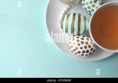 Oeufs de Pâques décorés avec bloc-notes florales et une tasse de thé à la menthe sur fond turquoise bleu sarcelle aqua with copy space Banque D'Images