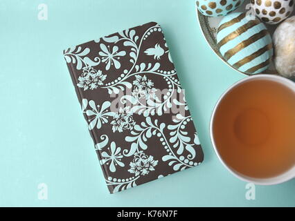 Oeufs de Pâques décorés avec bloc-notes florales et une tasse de thé à la menthe sur fond turquoise bleu sarcelle aqua with copy space Banque D'Images