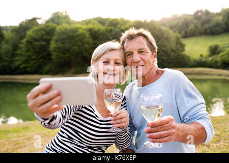 Couple au bord du lac un pique-nique en tenant selfies
